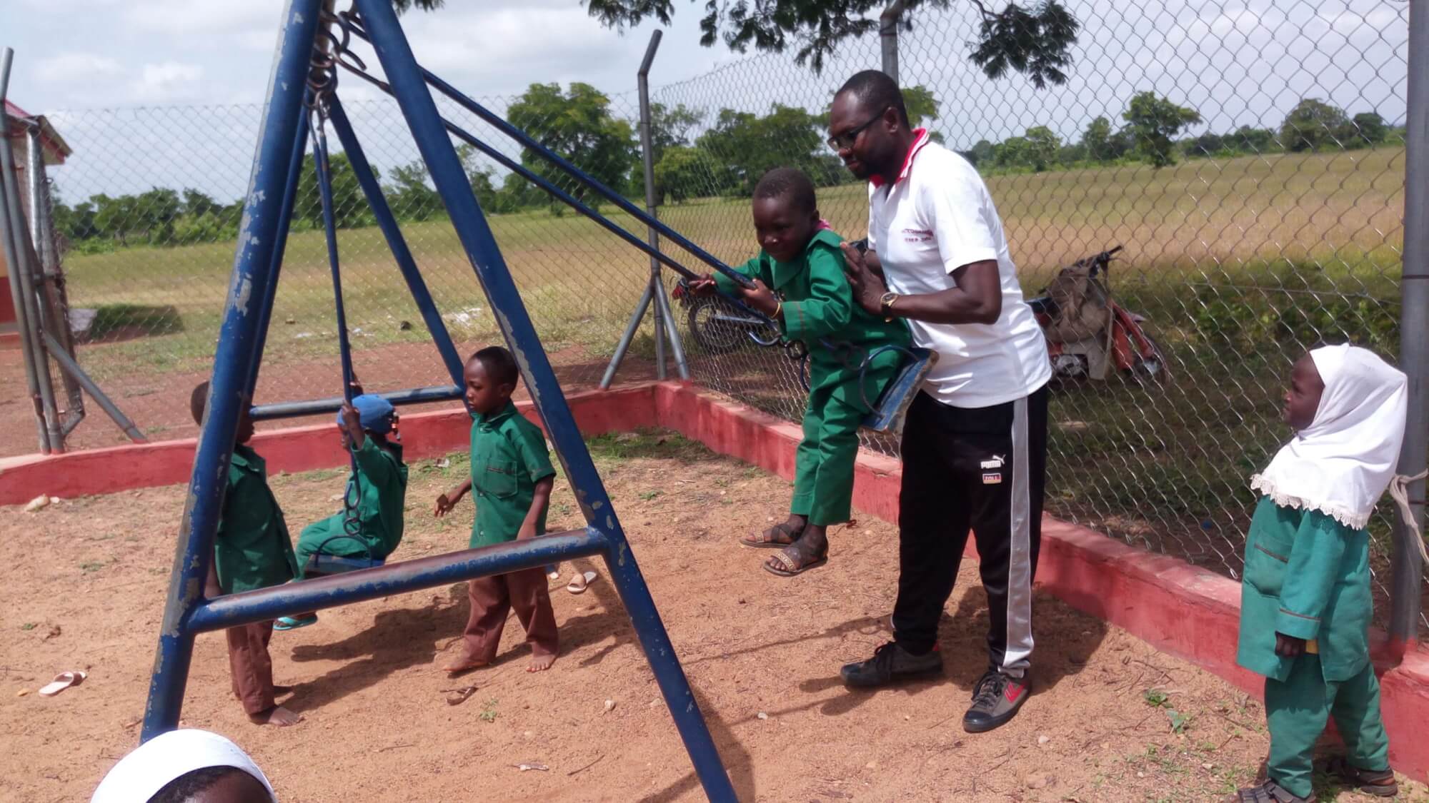 Researcher Pushing a Pupil on a Swing